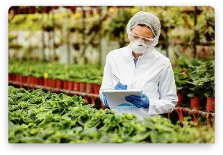 female-biotechnologist-inspecting-potted-plants-plant-nursery-writing-notes-into-clipboard